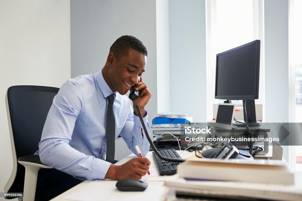 Young black businessman using the phone at his office desk Office Stock Photo