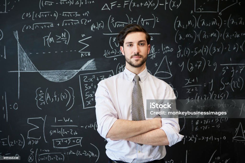 Junger Mann sucht Kamera vor einer Tafel - Lizenzfrei Mathematisches Symbol Stock-Foto