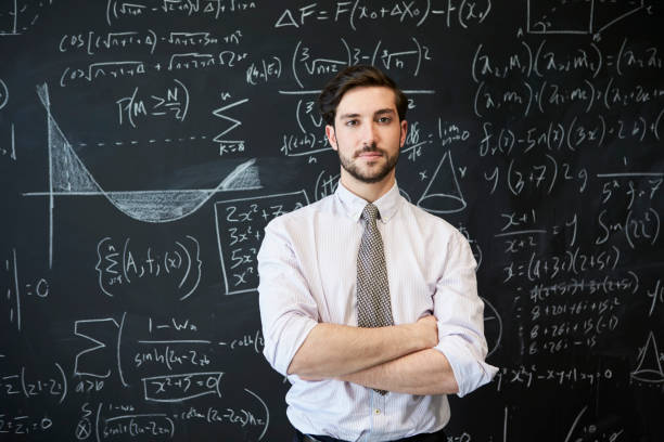 Young man looking to camera in front of a blackboard Young man looking to camera in front of a blackboard math teacher stock pictures, royalty-free photos & images