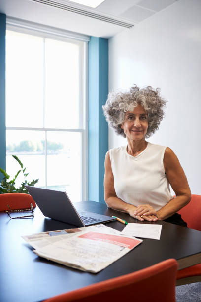istock Middle aged woman in an office smiling to camera, vertical 899355370