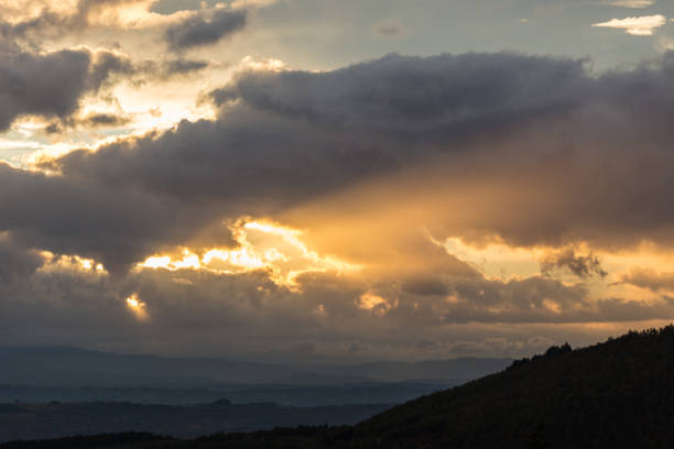 istock A silhouette of a mountain peak at sunset, beneath sun rays coming out through some clouds 899364066
