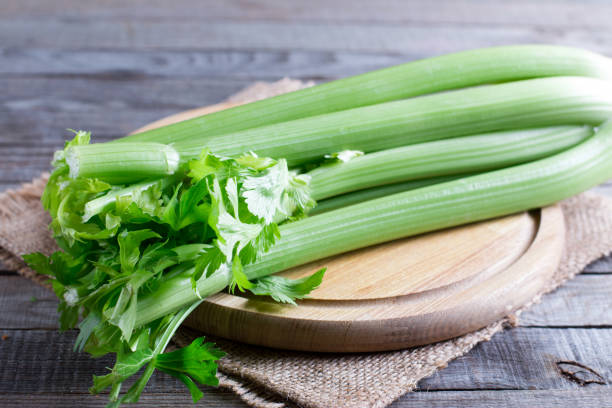 Fresh green celery stems on wooden cutting board Fresh green celery stems on wooden cutting board celery stock pictures, royalty-free photos & images