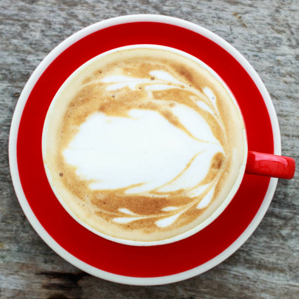 istock Top view latte art coffee isolate on wooden background. Red cup. 899384150