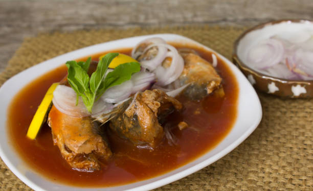 Canned fish with tomato sauce in white plate On old wood floor Canned fish with tomato sauce in white plate On old wood floor. proteína stock pictures, royalty-free photos & images