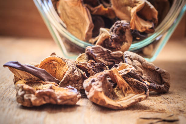 istock Dry mushrooms in jar on wooden table. 899405786