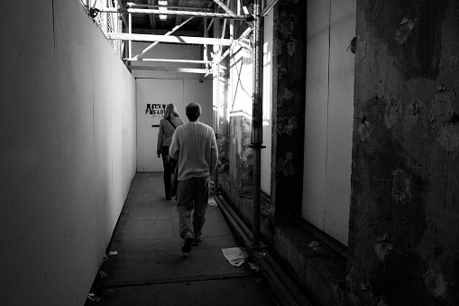 A man and woman walk througha shadowed passageway in the city