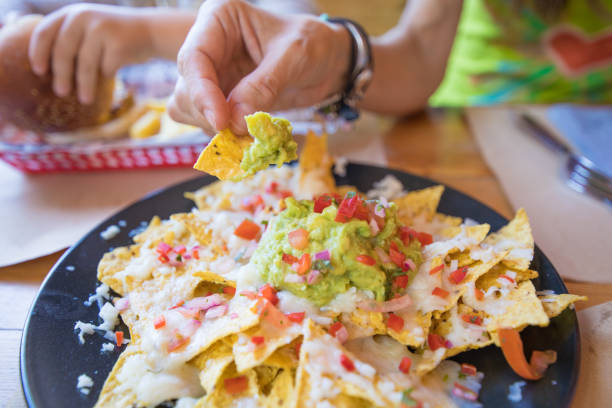 istock hand dipping nacho in guagamole from black plate 899415532