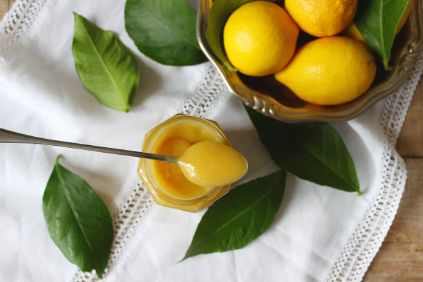 istock Lemon curd in a glass jar, lemons and lemon leaves. Rustic style, selective focus. 899422726