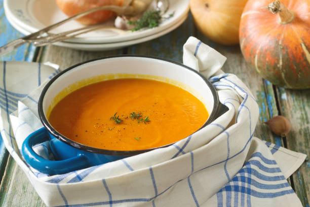 istock Pumpkin cream soup in a blue saucepan on a wooden background. Rustic style, selective focus. 899426710