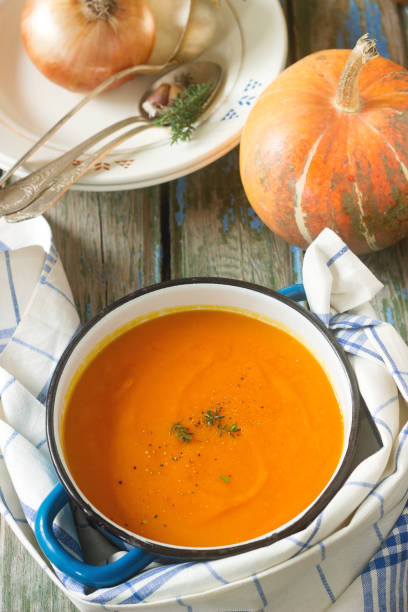 istock Pumpkin cream soup in a blue saucepan on a wooden background. Rustic style, selective focus. 899427042
