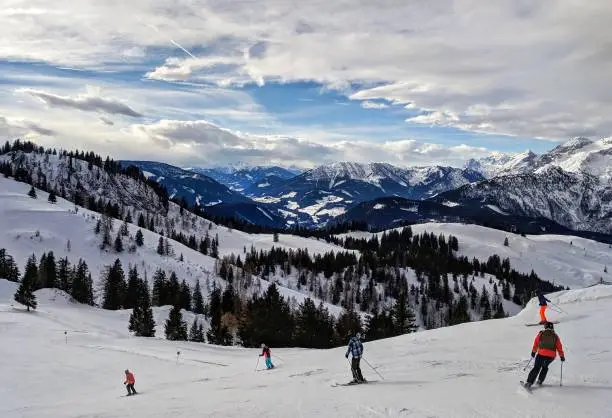 Unidentifiable people skiing down groomed slopes at a ski resort in Dachstein West, Austria, 27 December,  2017