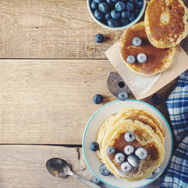 Stack of pancakes with blueberries on wooden table, rustic