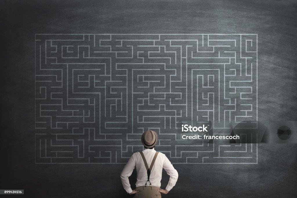 man try to solve a labyring on a chalkboard Maze Stock Photo