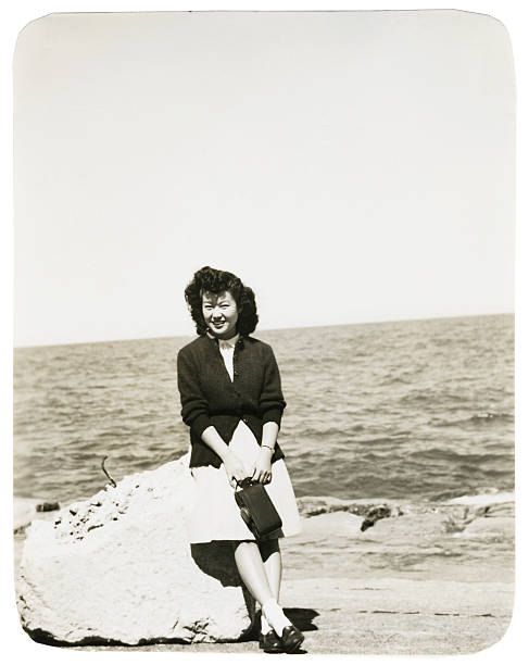 Asian Woman Sitting on a Rock at the Beach stock photo