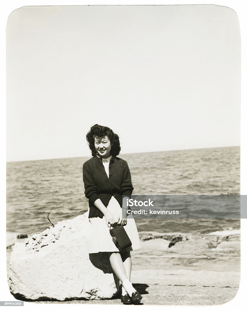 Mulher asiática, sentado em uma pedra na praia - Foto de stock de Preto e branco royalty-free