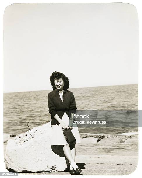 Foto de Mulher Asiática Sentado Em Uma Pedra Na Praia e mais fotos de stock de Preto e branco - Preto e branco, Estilo retrô, Fotografia - Imagem