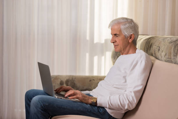 istock Senior man using laptop at home and surfing the net 899450620