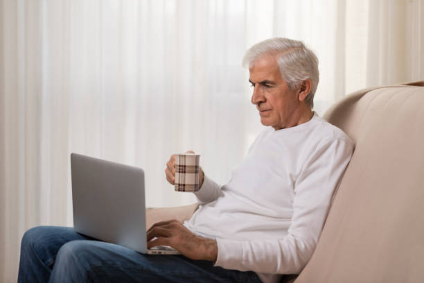istock Mature man using laptop during coffee time at home 899450678