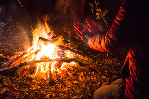 istock girl warms her hands from the fire in the night forest 899454488