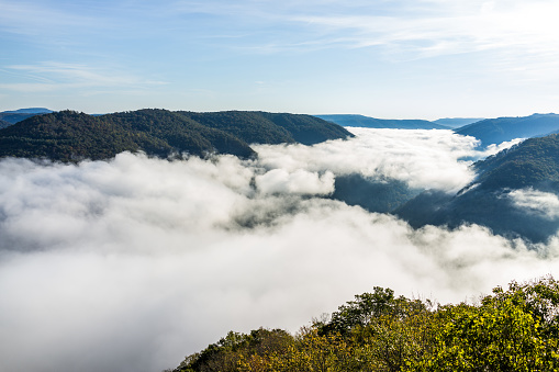 Mountains and fog, mist clouds in morning floating above forest trees, covering, blanketing valley in Grandview Overlook, West Virginia