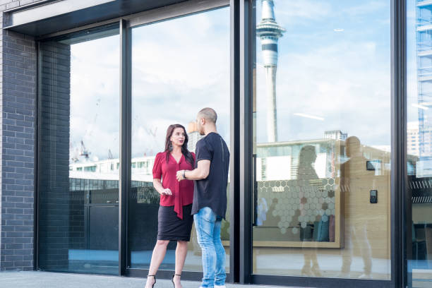 istock Manager having conversation with maori employee outside modern office building with Sky Tower reflected in glass. Auckland, New Zealand, NZ 899476756