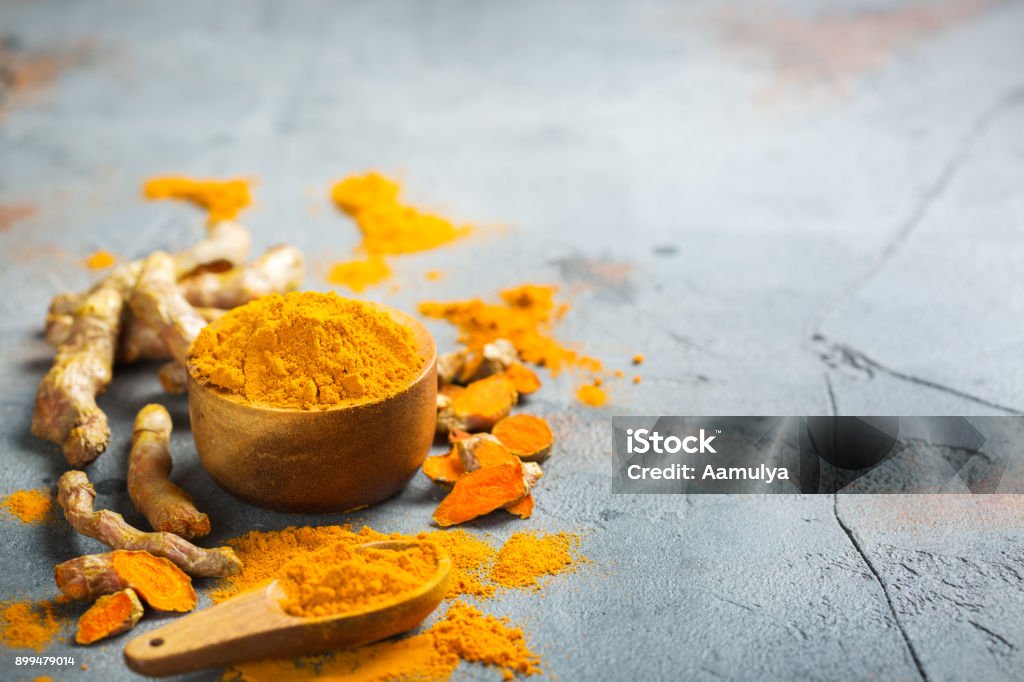 Raw turmeric root curcuma longa powder Food and drink, diet nutrition, health care concept. Raw organic orange turmeric root and powder, curcuma longa on a grunge cooking table. Indian oriental low cholesterol spices Turmeric Stock Photo