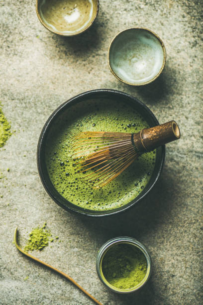 Matcha powder, Chashaku spoon, Chasen bamboo whisk, Chawan bowl, cups Flat-lay of Japanese tools for brewing matcha tea. Matcha powder in tin can, Chashaku spoon, Chasen bamboo whisk, Chawan bowl and cups for ceremony over concrete background, top view matcha tea photos stock pictures, royalty-free photos & images