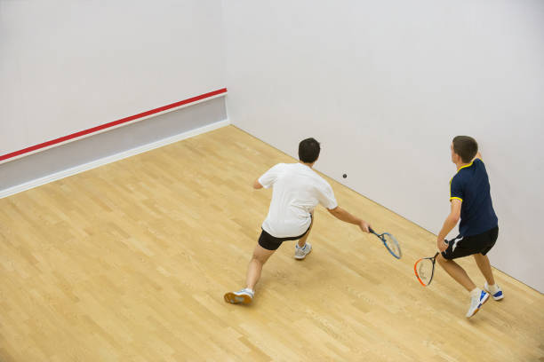 Two men playing match of squash. Squash players in action on squash court, back view. squash sport stock pictures, royalty-free photos & images