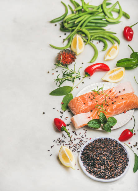 Raw salmon fillet steaks with vegetables, greens and rice