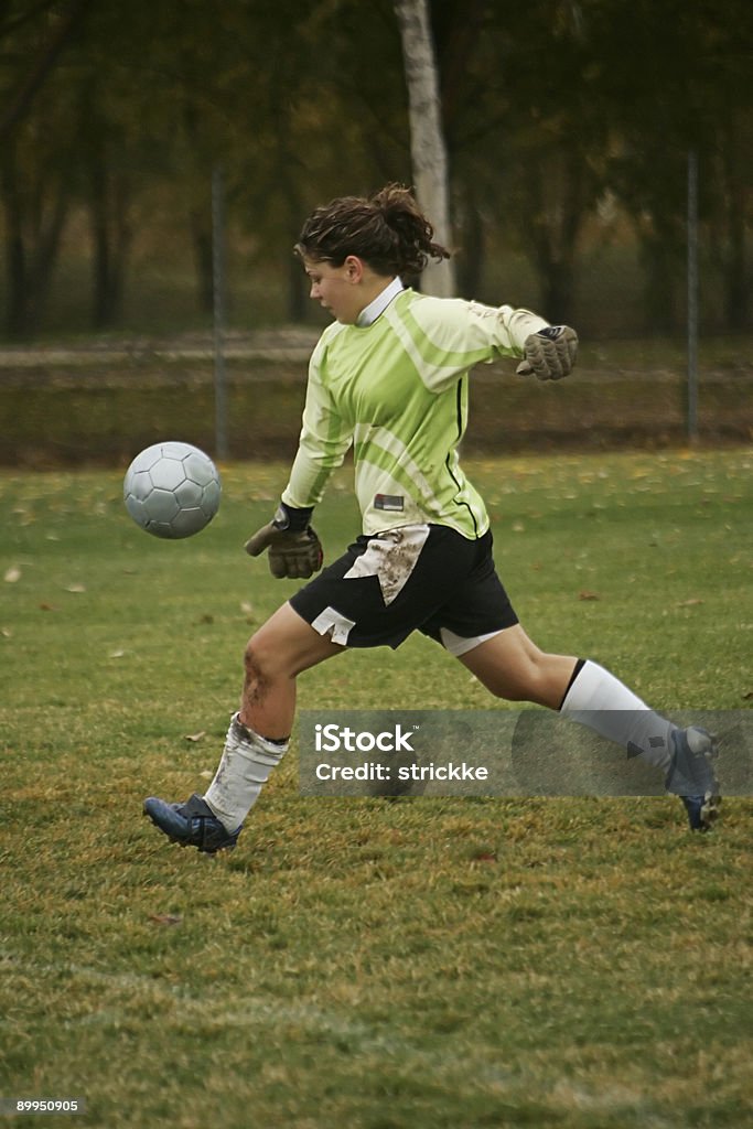 Femmina portiere in verde Agressively a-Kick Ball - Foto stock royalty-free di Bambino