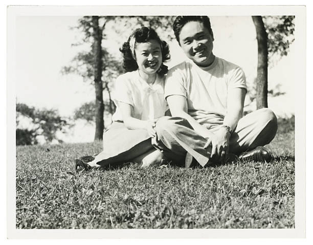 Asian Couple Sitting in the Grass stock photo