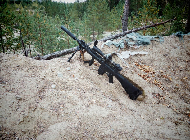 istock Assault rifle on the background of pine forests and sand 899530174
