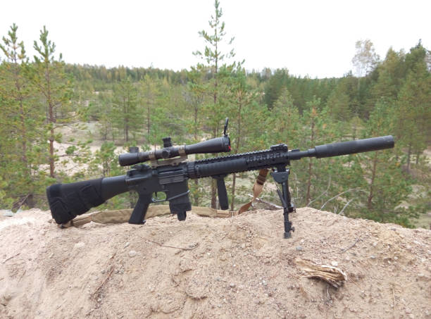 istock Assault rifle on the background of pine forests and sand 899530182