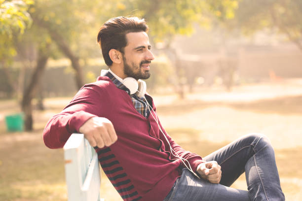 istock Man with headphones relaxing on park bench 899589820