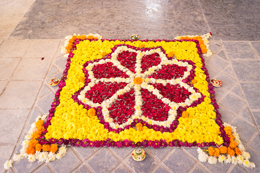 A yellow flower rangoli is made. Its a Indian tradition to put a rangoli at entrance on any auspicious occasions