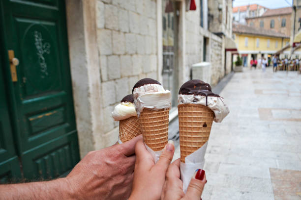 istock Hands Holding Vanilla Soft Serve Ice Cream Waffled Cone in A Summer Day. 899597650