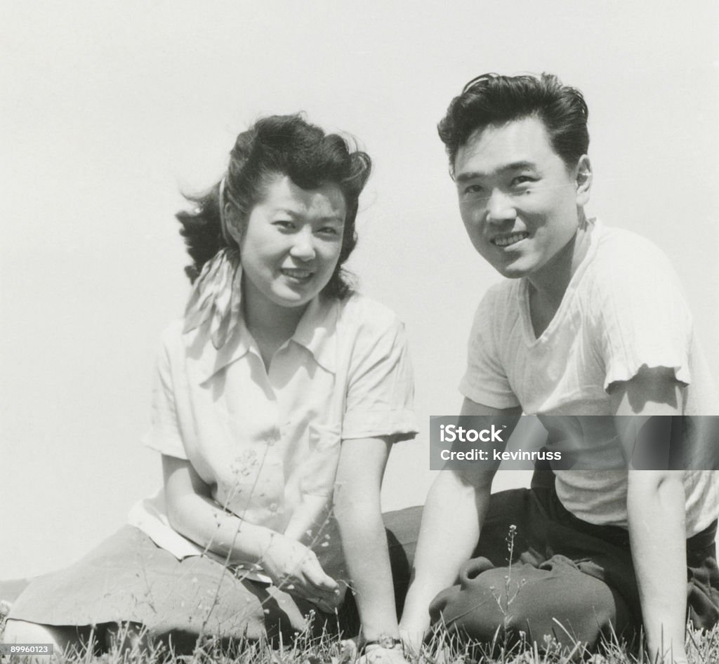Young Asian pareja sentada en el césped - Foto de stock de Anticuado libre de derechos