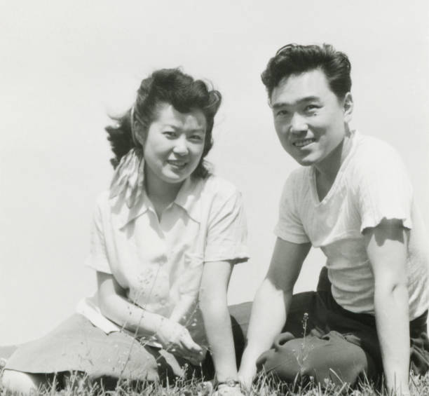 Young Asian Couple Sitting in the Grass stock photo