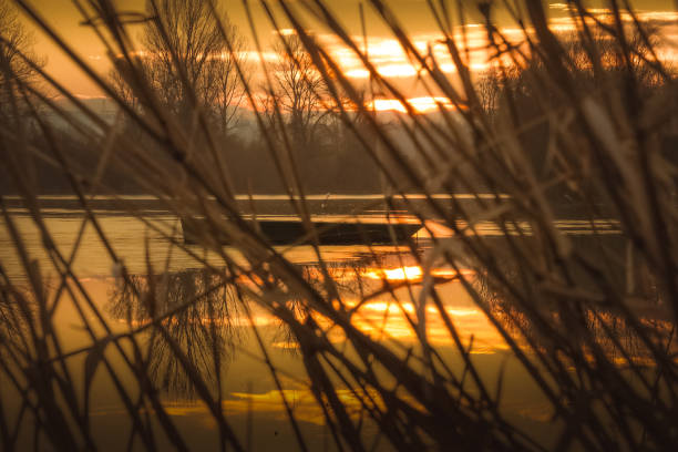 Late December on river Danube near Novi Sad, Serbia. One lonely fishing boat at winter sunset on half frozen river.