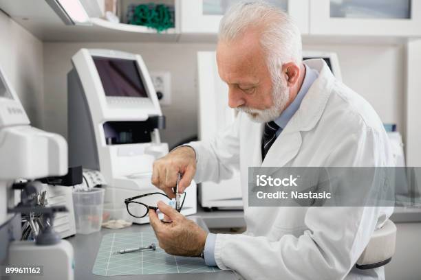 Optician Repairing Eye Glasses In Workshop With Professional Tools Stock Photo - Download Image Now