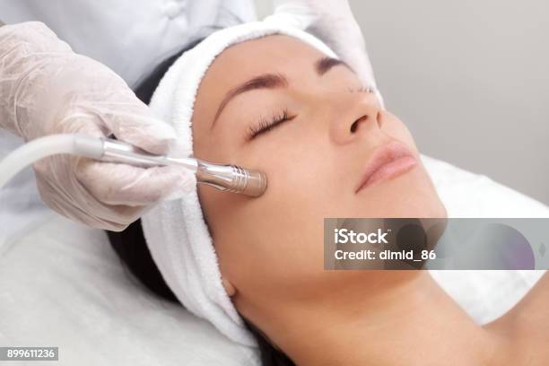 Photo libre de droit de Lesthéticienne Rend La Procédure Microdermabrasion De La Peau Du Visage Dune Belle Jeune Femme Dans Un Salon De Beauté banque d'images et plus d'images libres de droit de Microdermabrasion