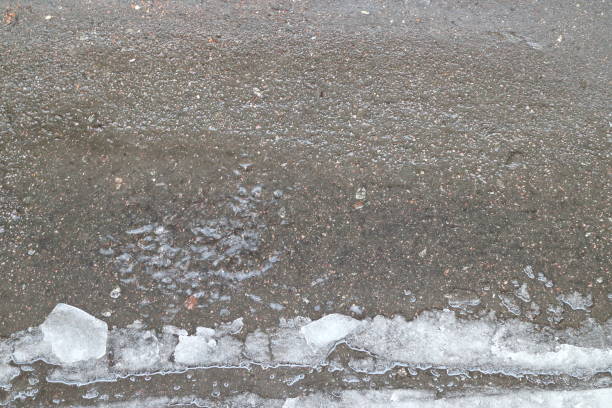 istock a puddle in which water drips on the asphalt and snow 899619896