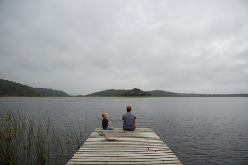 A young boy enjoys fishing off the jetty with his father