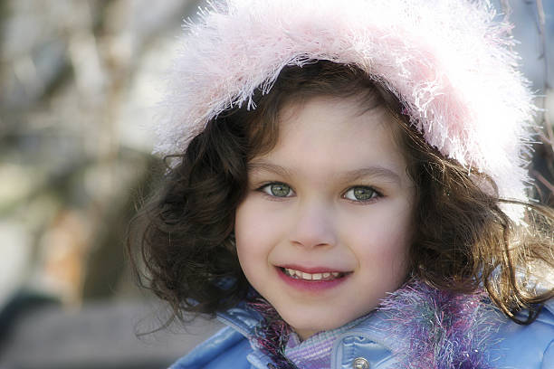 Close-up portrait of cute serious girl. Female child is wearing warm clothing. She is having blue eyes.