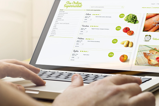 online shopping concept: man using a laptop with supermarket website on the screen. Screen graphics are made up.