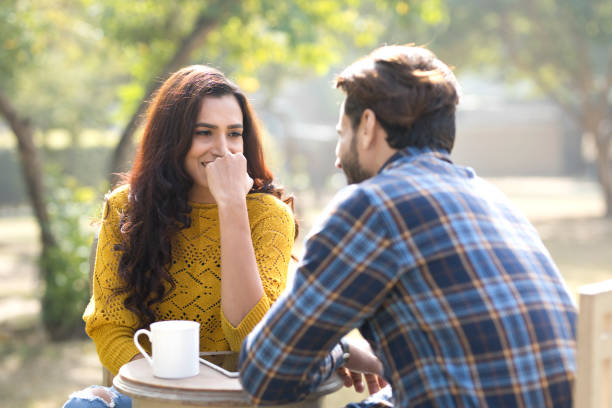 Romantic Indian couple having coffee at park Happy young couple with digital tablet and coffee cup at park flirting stock pictures, royalty-free photos & images