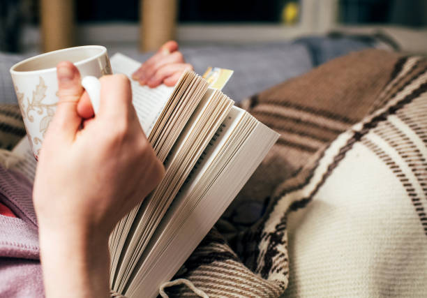 istock Generic image of Woman reading book drinking hot tea 899641442