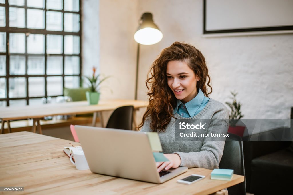 Giovane donna di successo in ufficio moderno che lavora su laptop. - Foto stock royalty-free di Computer portatile