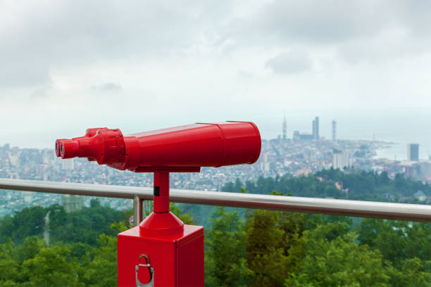 Coin operated red binocular towerview on observation deck with view on the sea and city