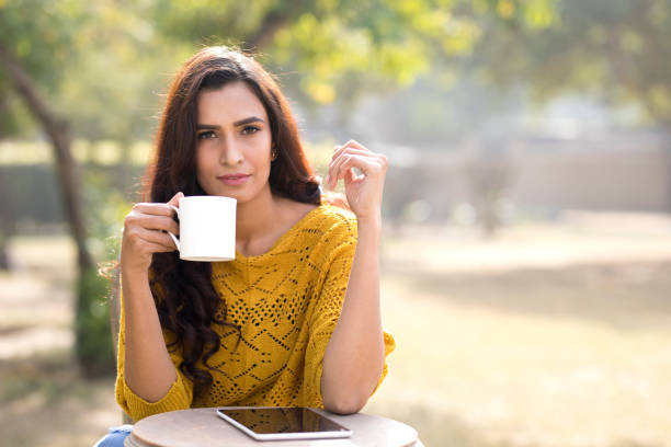 istock Beautiful woman drinking coffee at park 899658524